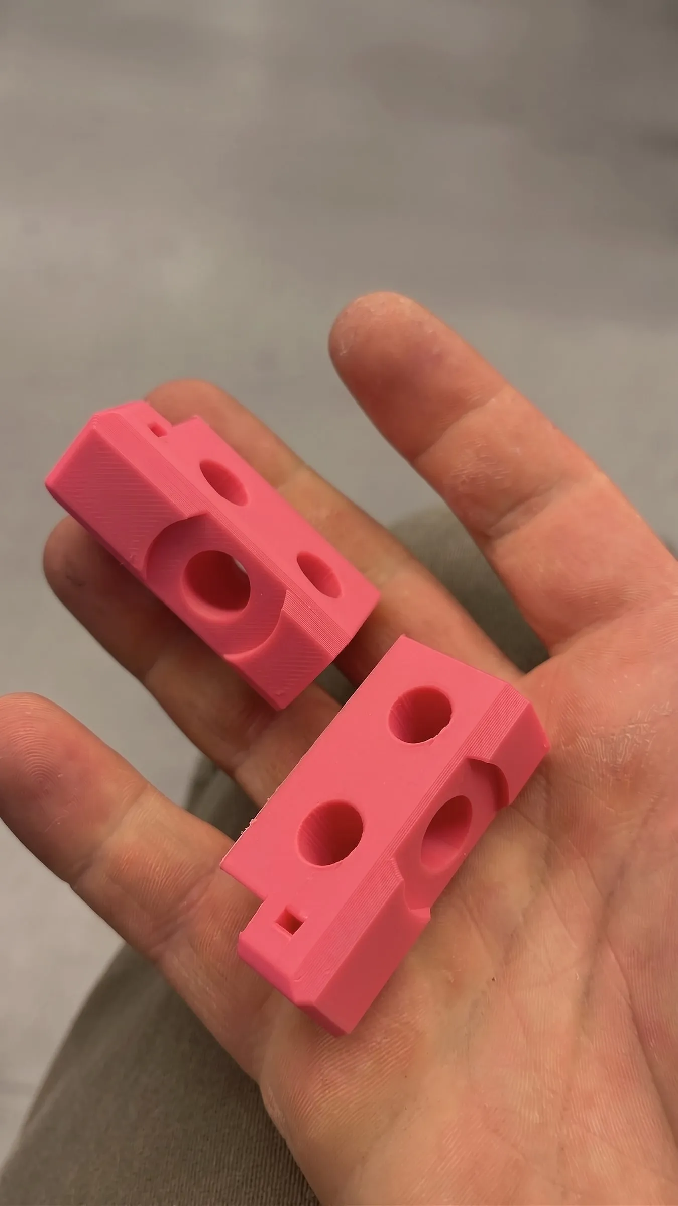 Twee roze 3D-geprinte onderdelen in een hand